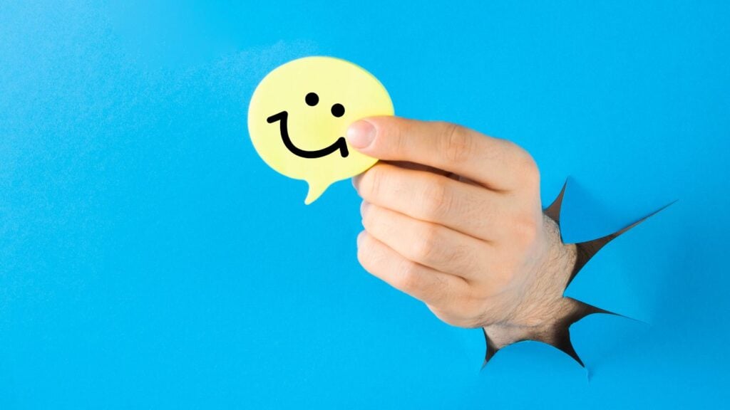 一只人手握着一个带有笑脸的黄色语音气泡